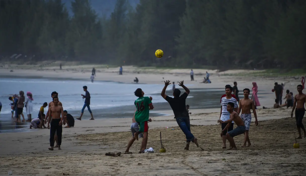 Wisatawan bermain bola saat berlibur Lebaran di Pantai Lhoknga, Aceh Besar, Aceh, Minggu (9/6/2019). (CHAIDEER MAHYUDDIN/AFP)