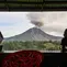 Dua pria menyaksikan Gunung Sinabung menyemburkan abu dan asap tebal dari wilayah Karo, Provinsi Sumatra Utara, Rabu, 2 September 2026. (AFP/ YT Haryono)