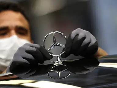 Karyawan menempelkan lambang saat merakit mobil Mercedes-Benz S-class di pabrik Mercedes, Sindelfingen, Jerman, Kamis (30/4/2020). Mulai 27 April 2020, Mercedes-Benz kembali membuka jalur produksi yang sebelumnya ditutup karena pandemi virus corona COVID-19. (AP Photo/Matthias Schrader)