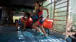 Atlet triathlon Kuba, Leslie Amat berlari dengan tali di pinggangnya di bawah pengawasan sang pelatih, Dioseles Fernandez di teras rumahnya di Havana, Senin (20/4/2020). Atlet Kuba tak bisa berlatih di fasilitas olahraga seperti biasanya selama pademi corona. (AP /Ismael Francisco)