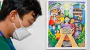 Pengunjung melintas di depan karya lukis yang bertajuk 'Membangun Harmoni' di Museum Basoeki Abdullah, Jakarta, Sabtu (18/12/2021). 'Membangun Harmoni' tersebut merupakan hasil karya lomba dari pelajar di tingkat SD, SMP, hingga SMA. (Liputan6.com/Herman Zakharia)