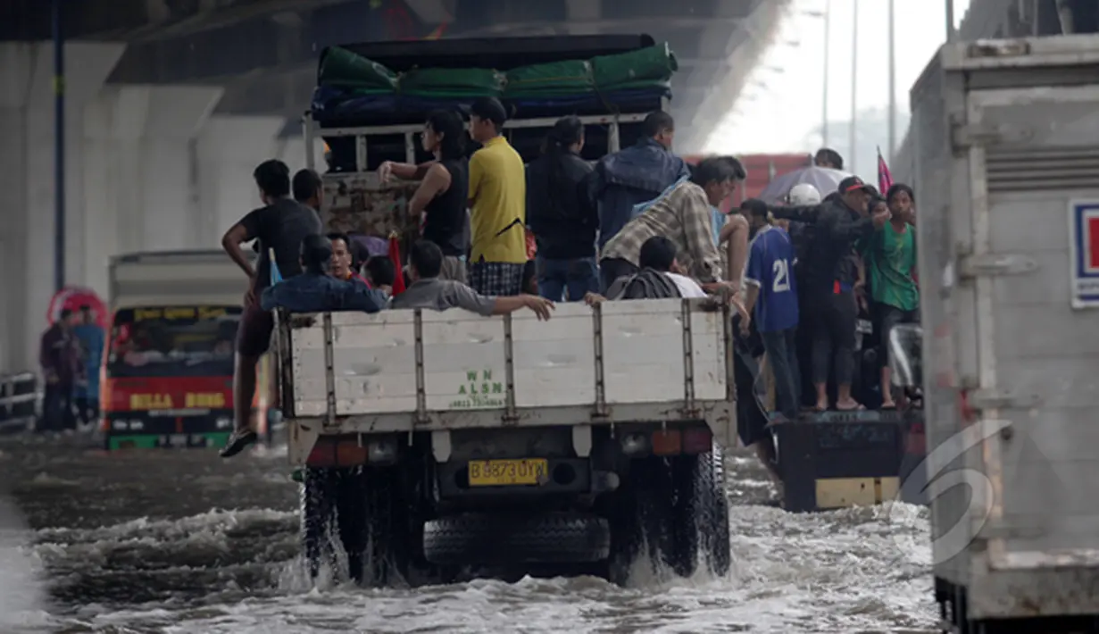 Sejumlah orang menaiki truk yang lewat untuk melalui banjir di jalan R.E Martadinata, Jakarta, Senin (6/2/2015). (Liputan6.com/Faizal Fanani)
