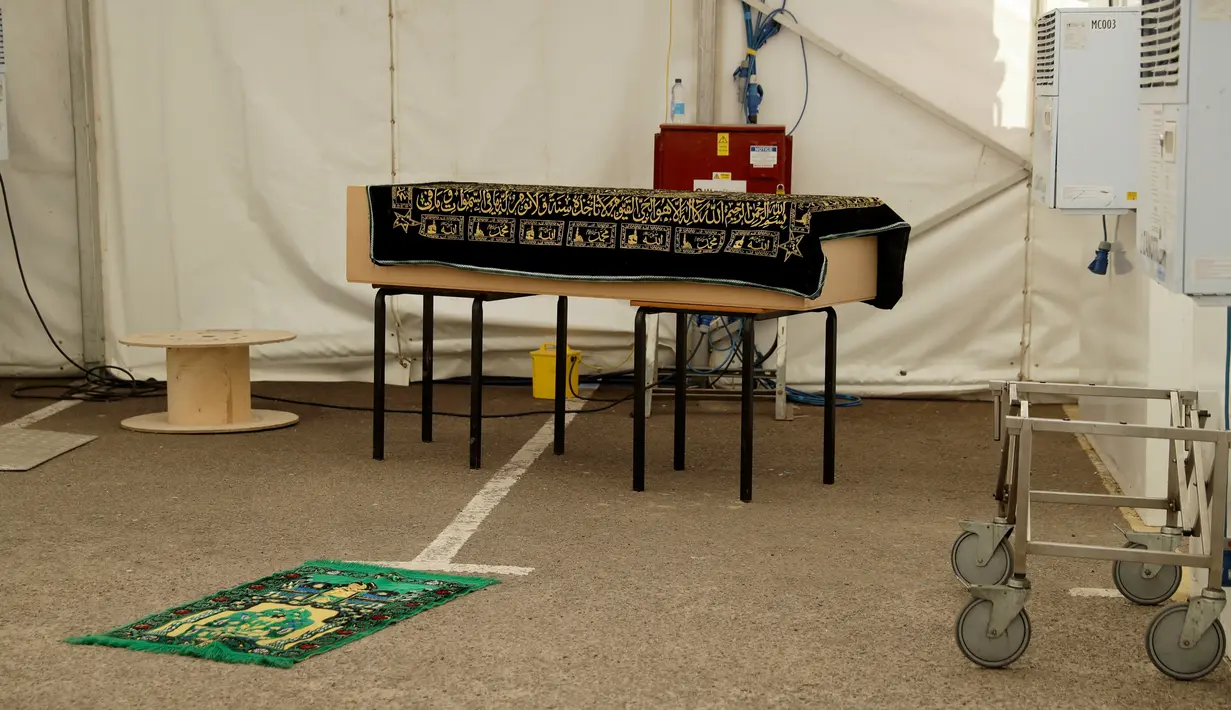 Peti mati berisi jenazah korban COVID-19 diletakkan di atas meja sebelum penguburan, di halaman parkir Central Jamis Mosque Ghamkol Sharif di Birmingham, Inggris pada 24 April 2020. Masjid itu mengubah tempat parkirnya menjadi kamar mayat sementara untuk korban virus corona. (AP/Matt Dunham)