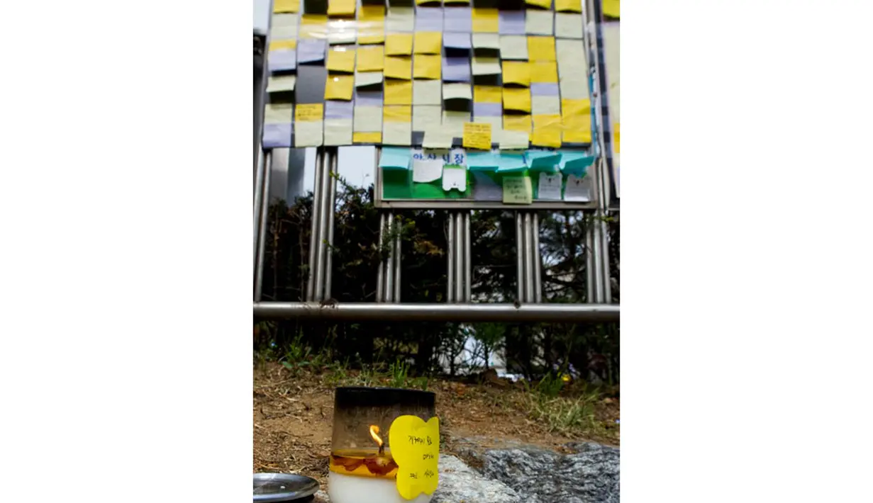 Sebuah lilin terlihat terus menyala di depan gerbang utama Ansan Danwon High School, Korea Selatan, Senin (21/4/2014) dalam peringatan mengenang tenggelamnya kapal feri Sewol. (AFP PHOTO/KIM DOO-HO)