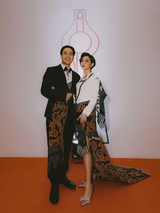 Potret couple goal Vidi Aldiano dengan Sheila Dara. Vidi tampil menawan dibalut setelan jas hitam dan kain batik sebagai rok, diberi pemanis kemeja putih dan dasi kupu-kupu, siluet modern yang tetap memancarkan aura mas-mas Jawa. Sedangkan Sheila tampil dengan atasan struktur putih dan rok batik yang serasi dengan yang dikenakan Vidi. [Foto: Instagram/sheiladaisha]