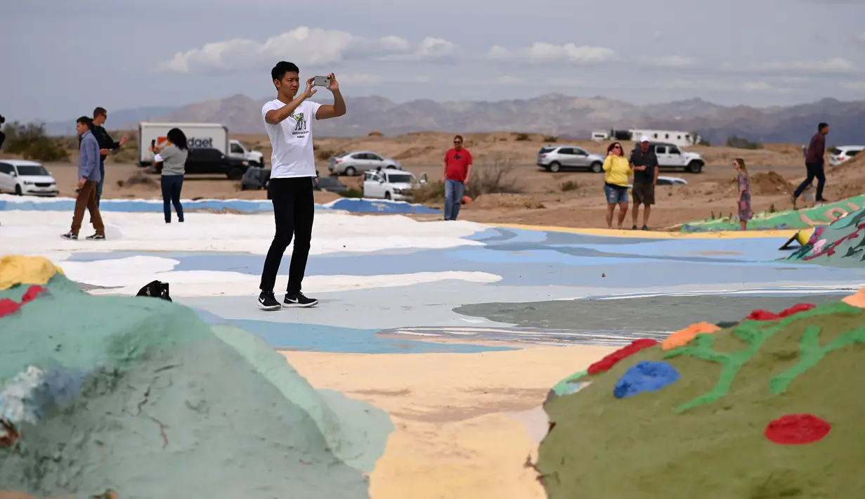 Turis mengunjungi Salvation Mountain, sebuah lereng bukti di Niland, California, Amerika Serikat. Salvation Mountain memiliki lebar 46 meter, dan panjang 15,2 meter ini tidak dihiasi pepohonan, melainkan tulisan dan gambar warna-warni dengan pesan cinta. (Robyn Beck/AFP)