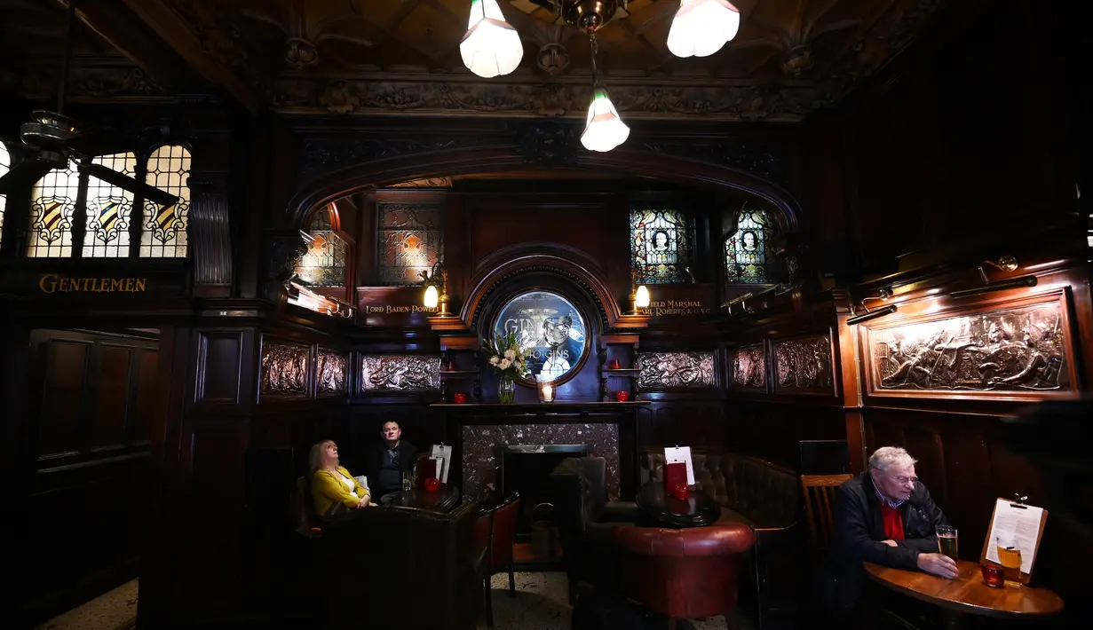 Orang-orang minum di pub Philharmonic Dining Rooms di Liverpool, Inggris pada 11 Februari 2020. Eksterior bagian dalam mulai dari ukiran dinding, kaca patri yang detail, dan perapian mahoni mengelilingi bar yang berbentuk tapal kuda. (Paul ELLIS / AFP)