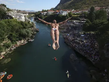 Seorang penyelam melompat dari Jembatan Tua selama kompetisi menyelam dari ketinggian ke-456 di Mostar, Bosnia, Minggu (31/7/2022). Sebanyak 31 penyelam dari Bosnia dan beberapa wilayah melompat dari jembatan setinggi 23 meter ke Sungai Neretva. (AP Photo/Armin Durgut)