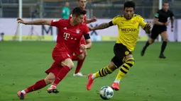 Striker Bayern Munchen, Robert Lewandowski, berebut bola dengan gelandang Borussia Dortmund, Jadon Sancho, pada laga pekan ke-28 Bundesliga di Stadion Signal Iduna Park, Selasa (26/5/2020) waktu setempat. Bayern Munchen menang 1-0 atas Borussia Dortmund. (AFP/Federico Gambarini/Pool)