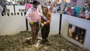 Miss Texas Margana Wood didampingi pawang ular Travis Gardner mengangkat ular derik saat acara Swingter Rattlesnake Sweetwater di Nolan County Coliseum (10/3). (AFP/Loren Elliot)