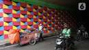 Pengguna jalan melintasi tembok kolong jembatan Stasiun Kereta Api Cawang yang dihiasi mural bernuansa kemerdekaan di Jakarta, Rabu (12/8/2020). Pembuatan mural di lokasi dilakukan dalam rangka menyambut Hari Ulang Tahun (HUT) ke-75 Kemerdekaan RI. (Liputan6.com/Immanuel Antonius)