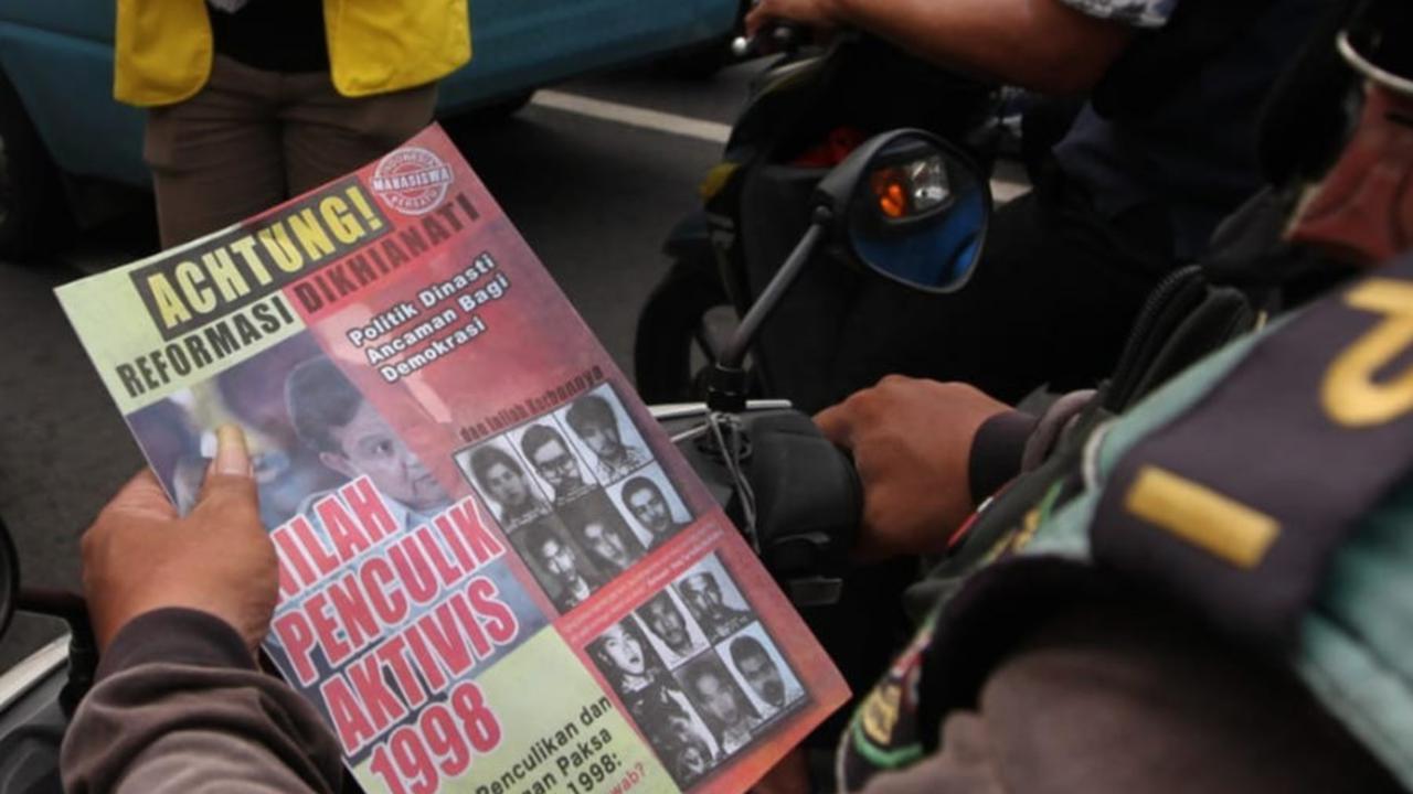 Pengendara sepeda motor membaca isi selebaran yang dibagikan mahasiswa UI.