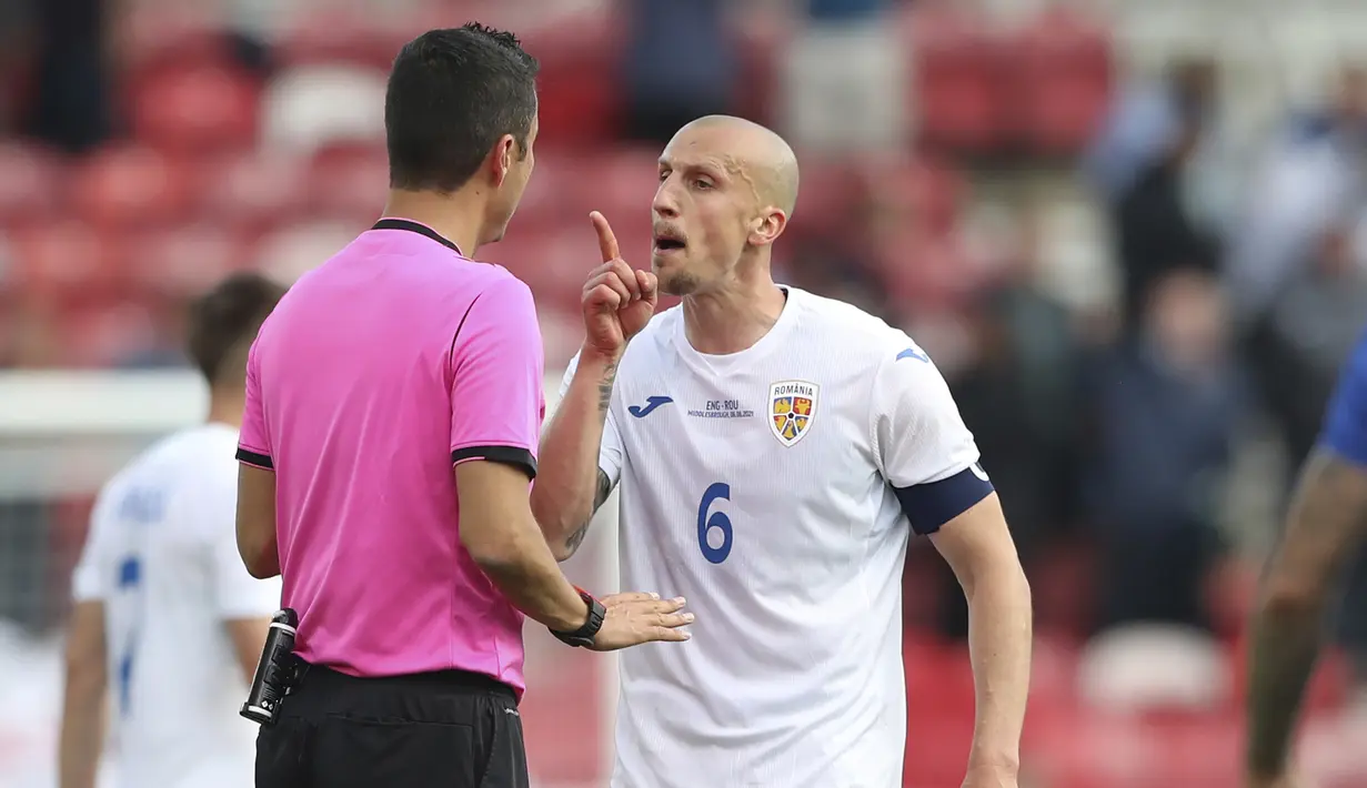 Bek Rumania, Vlad Chiriches (kanan) memprotes keputusan wasit Tiago Martins saat melawan Inggris dalam laga uji coba menjelang berlangsungnya Euro 2020 di Riverside Stadium, Middlesbrough, Minggu (6/6/2021). Rumania kalah 0-1 dari Inggris. (AP/Scott Heppell/Pool)