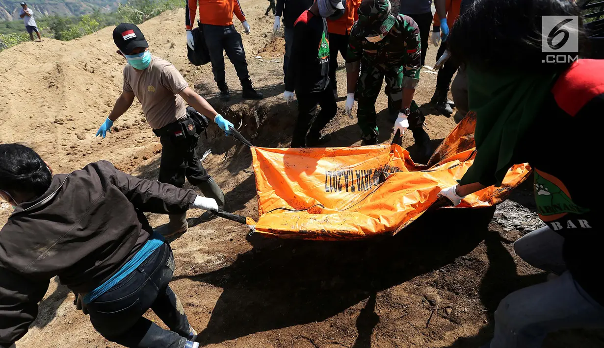 Petugas gabungan membawa kantong jenazah saat pemakaman massal di TPU Peboya Indah, Palu, Sulawesi Tengah, Rabu (3/10). Pemakaman massal tersebut memasuki hari ketiga setelah sebelumnya dilakukan di hari Senin. (Liputan6.com/Fery Pradolo)