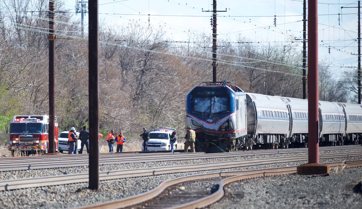 Personel darurat menyelidiki lokasi kereta Amtrak yang tergelincir setelah menabrak sebuah backhoe di dekat Philadelphia, Amerika Serikat, Minggu (3/4). Dua orang tewas dan 30 lainnya mengalami luka-luka akibat kejadian ini. (Mark Makela/Getty Images/AFP)