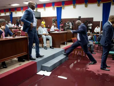 Seorang anggota parlemen melangkahi genangan air hujan pada lantai Gedung Parlemen Haiti di Port-au-Prince, Haiti, Rabu (21/8/2019). Bocornya atap pada Gedung Parlemen Haiti menyebabkan air masuk dan membasahi lantai. (AP Photo/Dieu Nalio Chery)