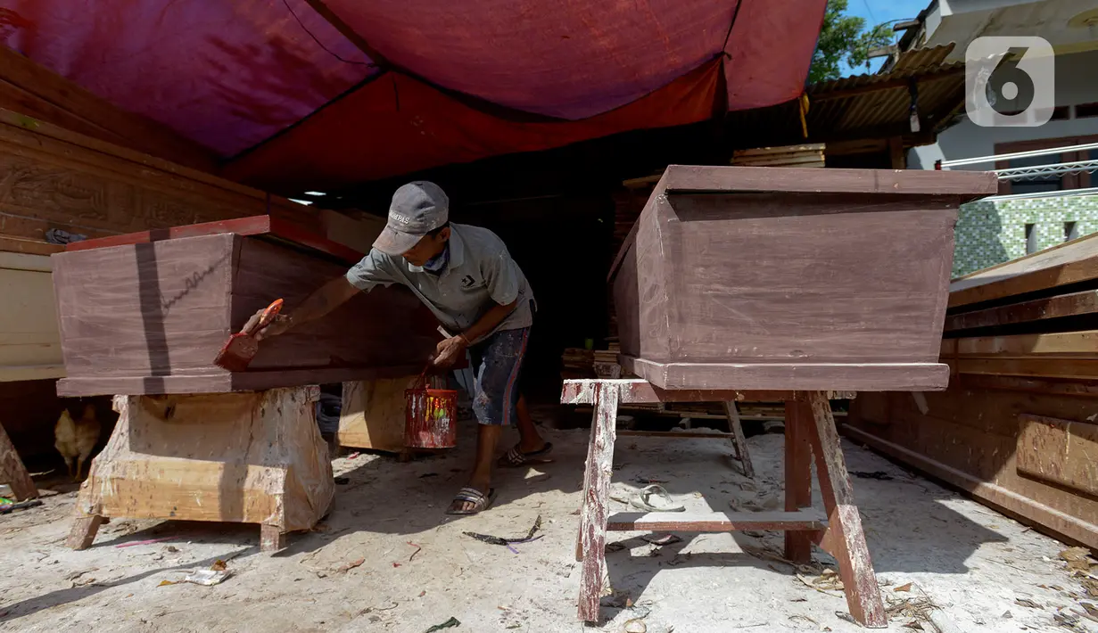 Herman pengrajin peti mati sedang mengecat pelitur untuk pembuatan peti mati di Pondok Kelapa, Jakarta Timur, Rabu (6/5/2020). Di tengah pandemi COVID-19 pembuatan peti mengalami kenaikan sekitar 15-30 peti di bandingkan hari biasanya. (merdeka.com/Imam Buhori)