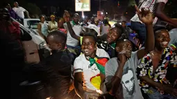 Warga Zimbabwe bernyanyi menyambut kabar Presiden Robert Mugabe mengundurkan diri di sebuah persimpangan pusat kota Harare, Selasa (21/11). Mugabe sebelumnya menolak untuk mengundurkan diri, meski ada pengambilalihan militer pekan lalu. (AP/Ben Curtis)