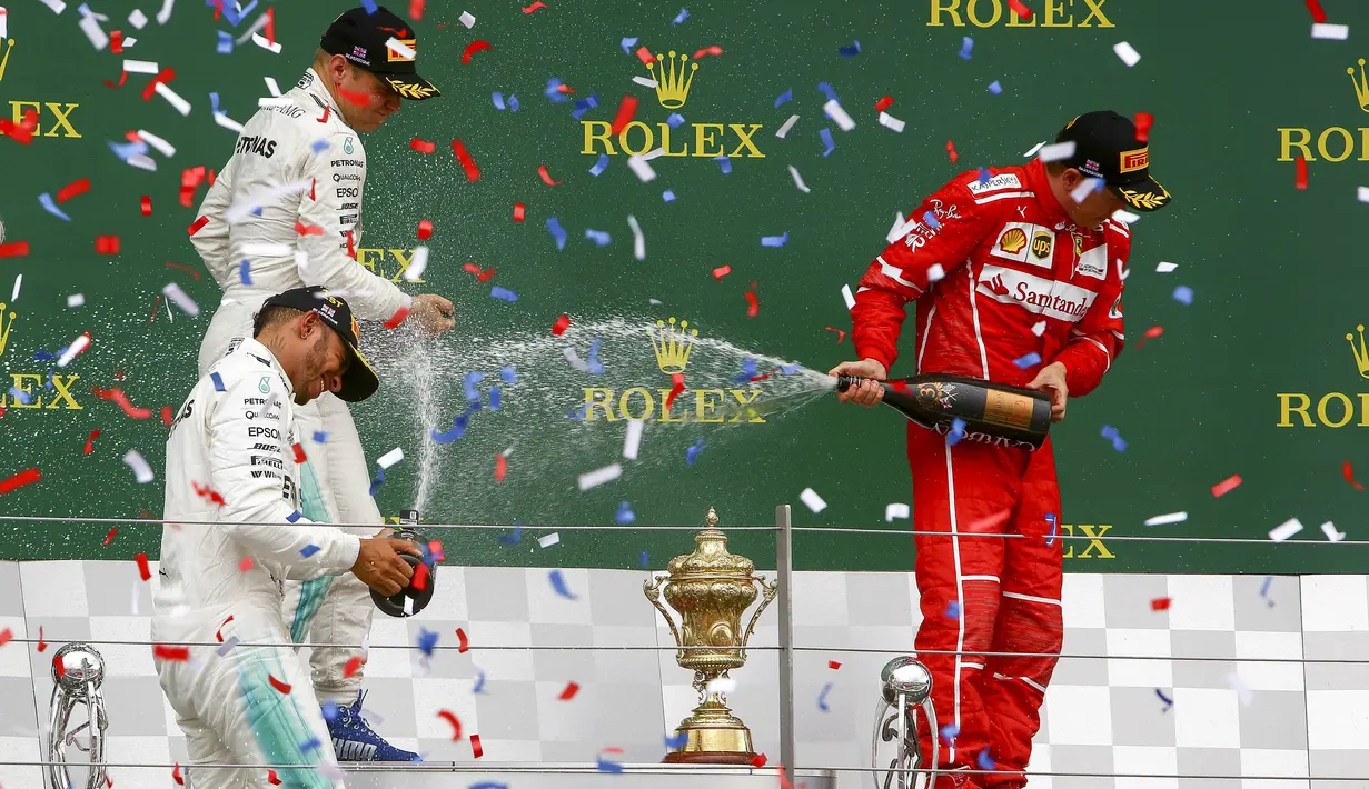 Lewis Hamilton bersama Valterri Bottas dan Kimi Raikkonen melakukan selebrasi di atas podium Sirkuit Silverstone, Minggu (16/7/2017). Pebalap asal Inggris itu melahap 51 lap dengan catatan waktu 1 jam 21 menit 27,430 detik. (EPA/Geoff Caddick)