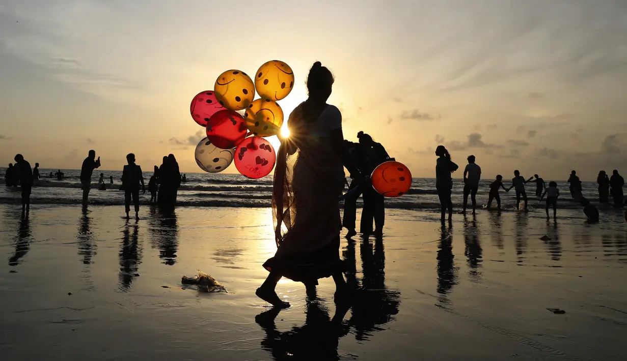 Seorang wanita menjual balon di Pantai Juhu, Mumbai, India, Selasa (24/8/2021). India mencatat penambahan 14.419 kasus positif COVID-19 pada 24 Agustus 2021. (AP Photo/Rafiq Maqbool)