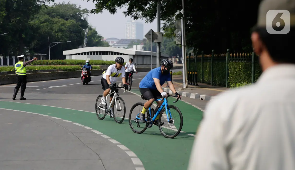 Petugas gabungan melakukan pengalihan jalur pesepeda di kawasan Sudirman-Thamrin, Jakarta, Minggu (5/9/2021). Pemberlakuan jalur ganjil genap pada masa PPKM membuat pengguna sepeda dilarang melintasi kawasan ganjil-genap pagi ini. (Liputan6.com/Angga Yuniar)