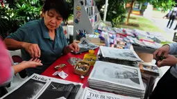 Warga membeli surat kabar setelah sehari meninggalnya mantan PM Singapura, Lee Kuan Yew, Singapura, Selasa (24/3/2015). Lee meninggal pada hari Senin (23/3) di usia 91 tahun dan wajahnya menghiasi berbagai media cetak Singapura. (AFP PHOTO/Mohd FYROL)