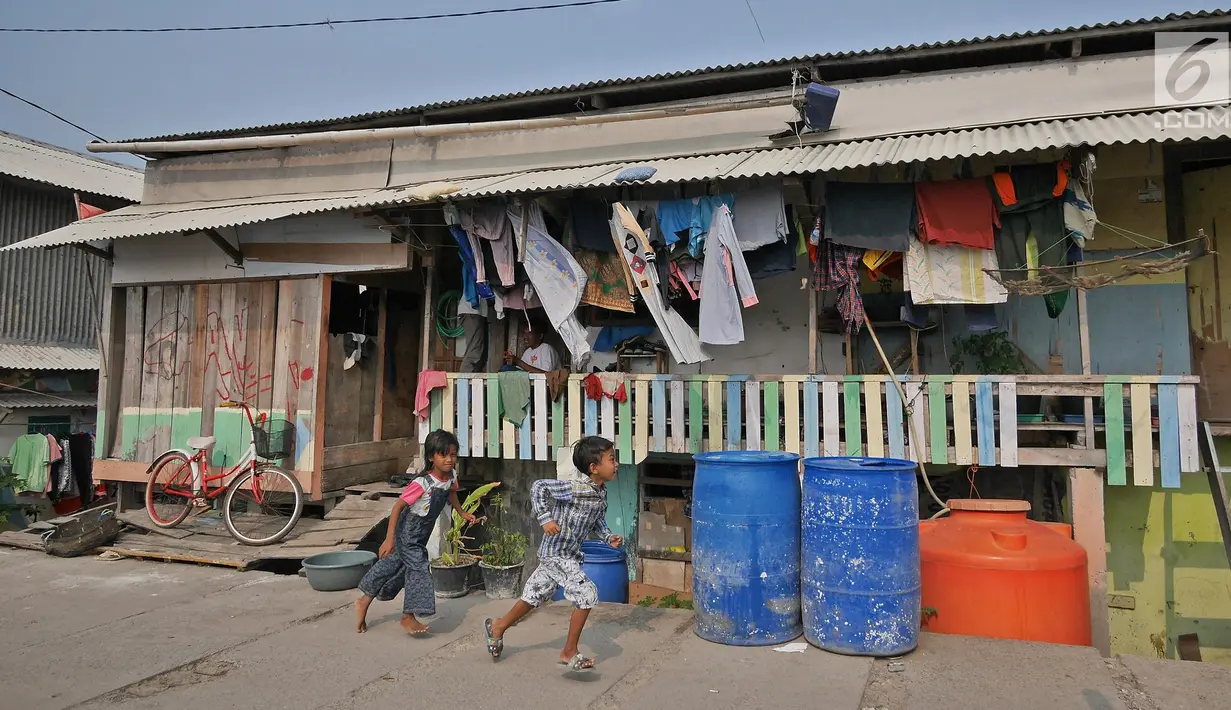 Anak-anak berlari melewati tong air di kawasan Kampung Kamal Muara, Jakarta, Selasa (9/7/2019). Sebagian besar warga Kampung Kamal Muara memasang pipa pada talang air di tepi atap rumah mereka untuk menampung air hujan. (Liputan6.com/Herman Zakharia)