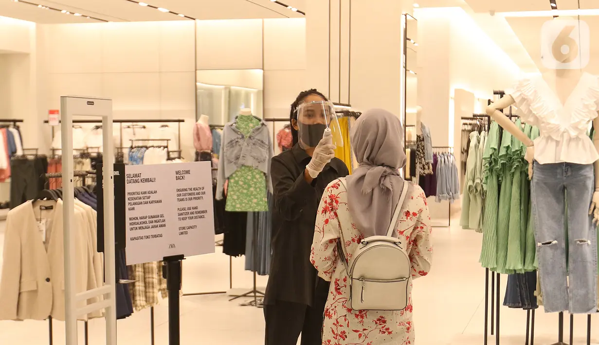 Petugas mengecek suhu pengunjung sebelum memasuki gerai pakaian di Mall Senayan City, Jakarta, Senin (15/6/2020). Pusat perbelanjaan atau mal di Jakarta kembali dibuka pada Senin (15/6) di masa PSBB transisi dengan jumlah pengunjung masih dibatasi hanya 50 persen. (Liputan6.com/Herman Zakharia)