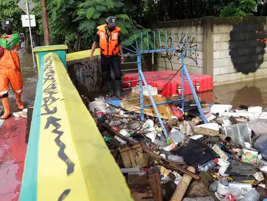 Petugas UPK Badan Air DLH Provinsi DKI Jakarta berjibaku membersihkan tumpukan sampah yang menghalangi aliran air Kali Mampang di Jalan Pejaten Raya, Jakarta, Sabtu (20/2/2021). Aliran air Kali Mapang di Jalan Pejaten Raya meluap akibat sumbatan tumpukan sampah. (Liputan6.com/Helmi Fithriansyah)