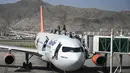 Orang-orang Afghanistan naik ke atas sebuah pesawat saat mereka menunggu di bandara Kabul (16/8/2021). Ribuan orang mencoba melarikan diri dari Taliban yang segera menguasai penuh Afghanistan. (AFP/Wakil Kohsar)