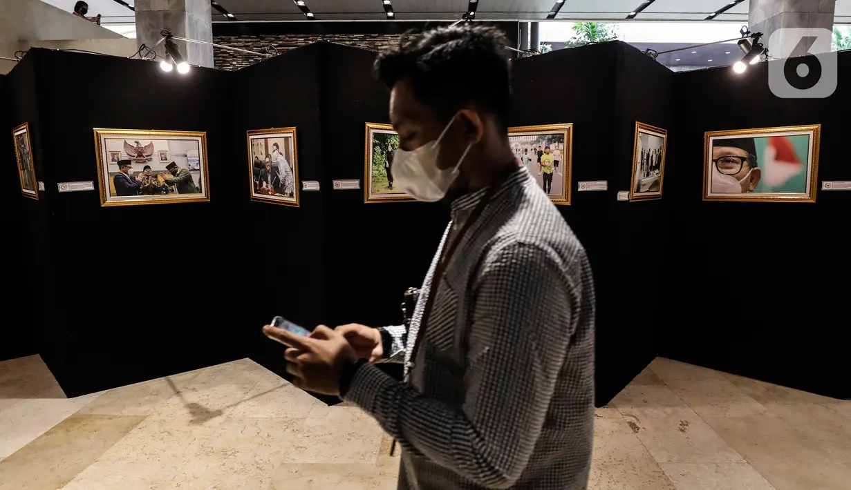 Pengunjung melintasi karya foto dalam Pameran Foto Jurnalistik Warna-Warni Parlemen dengan tema Bangkit Lebih Cepat di loby Nusantara II DPR, Senayan, Jakarta, Senin (29/8/2022). Pameran ini diikuti oleh 57 pewarta foto lintas media. (Liputan6.com/Johan Tallo)
