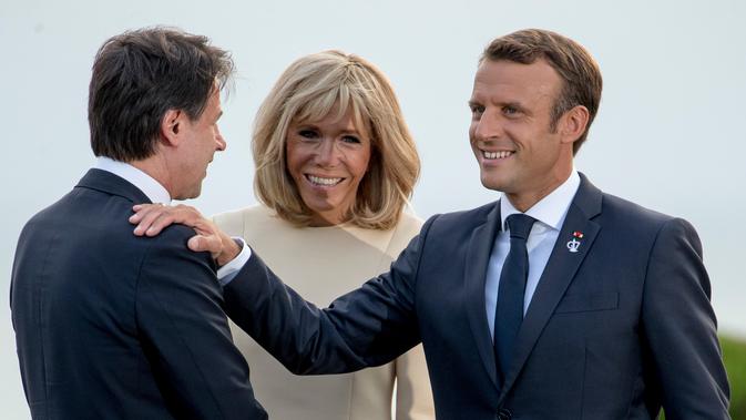 Presiden Prancis Emmanuel Macron (kanan) dan istrinya Brigitte Macron (tengah) menyambut kedatangan pemimpin sementara Italia Giuseppe Conte di KTT G7, Biarritz, Prancis, Sabtu (24/8/2019). (AP Photo/Andrew Harnik)