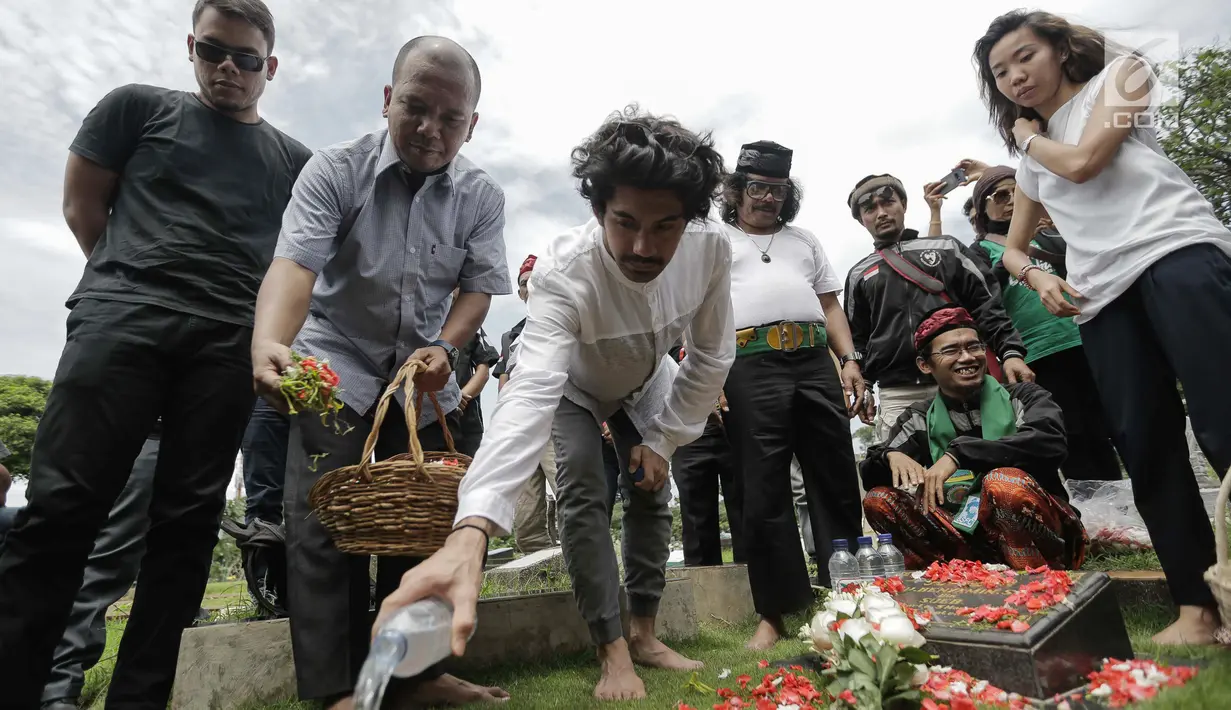 Aktor Reza Rahadian menyiramkan air di makam Benyamin Sueb di Karet Bivak, Jakarta, Jumat (26/1). Sebelum benar-benar menayangkan filmnya, Reza Rahadian dan para pemain lain berziarah ke makam Benyamin. (Liputan6.com/Faizal Fanani)