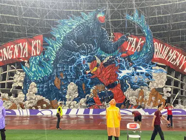 Koreografi raksasa dari suporter La Grande bergambar raksasa bergambarkan pertarungan antara Gundala dan Godzilla, serta tulisan "Untungnya Ku Tak Pilih Menyerah" di sisi kiri dan kanannya saat laga lanjutan putaran ketiga Grup C Kualifikasi Piala Dunia 2026 antara Timnas Indonesia melawan Jepang di Stadion Utama Gelora Bung Karno (SUGBK), Senayan, Jakarta, Jumat (15/11/2024). (Bola.com/Bagaskara Lazuardi)