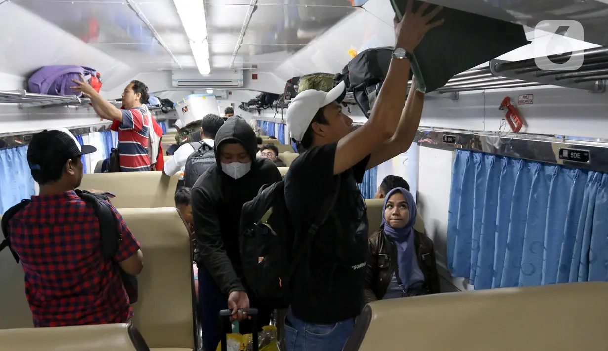 Penumpang menaikkan barang bawaan di dalam gerbong Kereta Api Jarak Jauh (KAJJ) di Stasiun Pasar Senen, Jakarta, Rabu (26/3/2025). (Liputan6.com/Herman Zakharia)