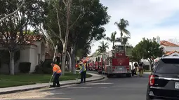 Petugas membersihkan puing helikopter yang jatuh menghantam sebuah rumah di Newport Beach, California, Selasa (30/1). Tiga orang tewas dan dua lainnya terluka dalam kecelakaan helikopter yang jatuh di lingkungan perumahan tersebut. (AP Photo/Amy Taxin)