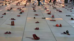 Orang-orang berjalan melewati instalasi ratusan sepatu merah untuk memprotes kekerasan terhadap perempuan di kota pesisir Tel Aviv, Selasa (4/12). Sepanjang tahun ini, 24 perempuan Israel tewas akibat tindakan kekerasan dalam rumah tangga. (JACK GUEZ/AFP)