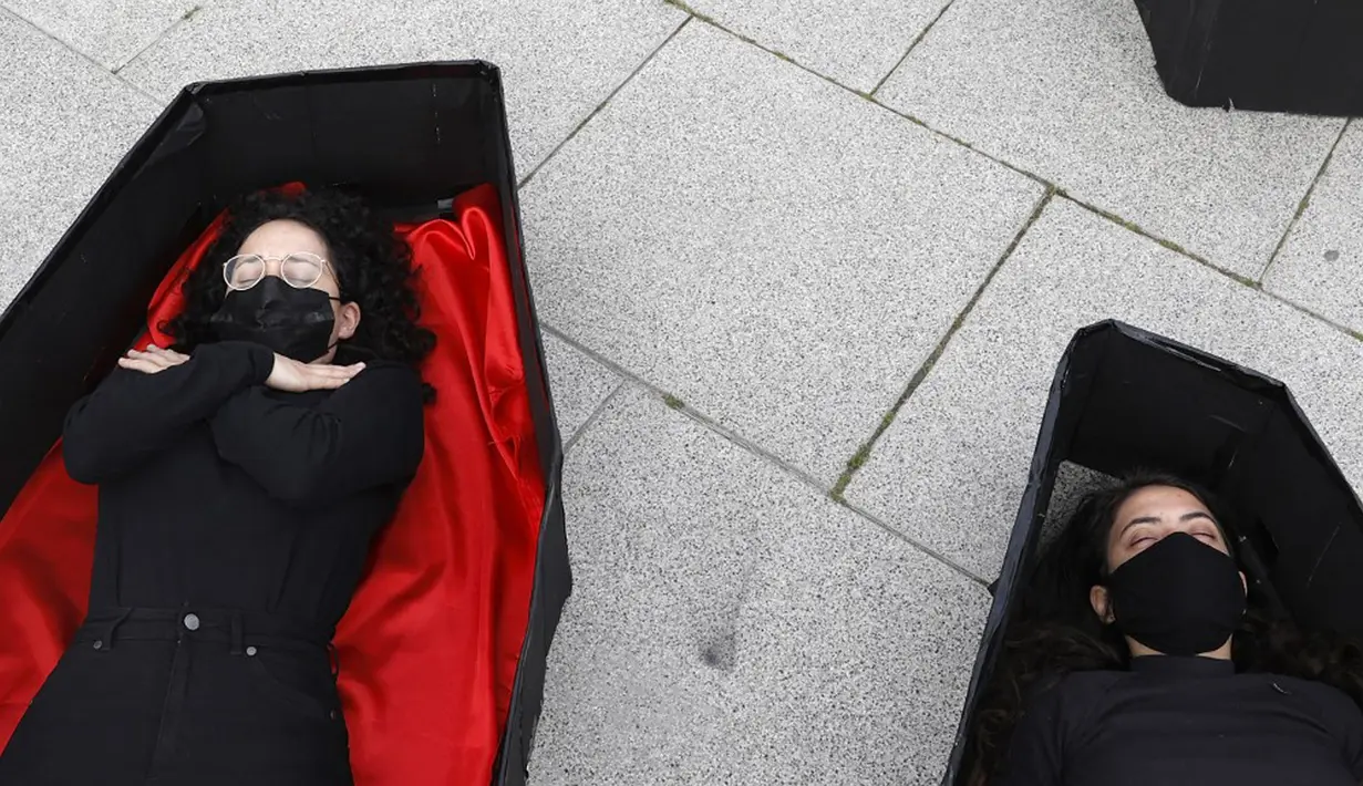 Para wanita berbaring dalam peti mati tiruan untuk mewakili mereka yang tewas akibat kekerasan dalam rumah tangga jelang Hari Perempuan Internasional di luar Pengadilan Distrik, Tel Aviv, Israel, Minggu (7/3/2021). Hari Perempuan Internasional dirayakan setiap tanggal 8 Maret. (JACK GUEZ/AFP)