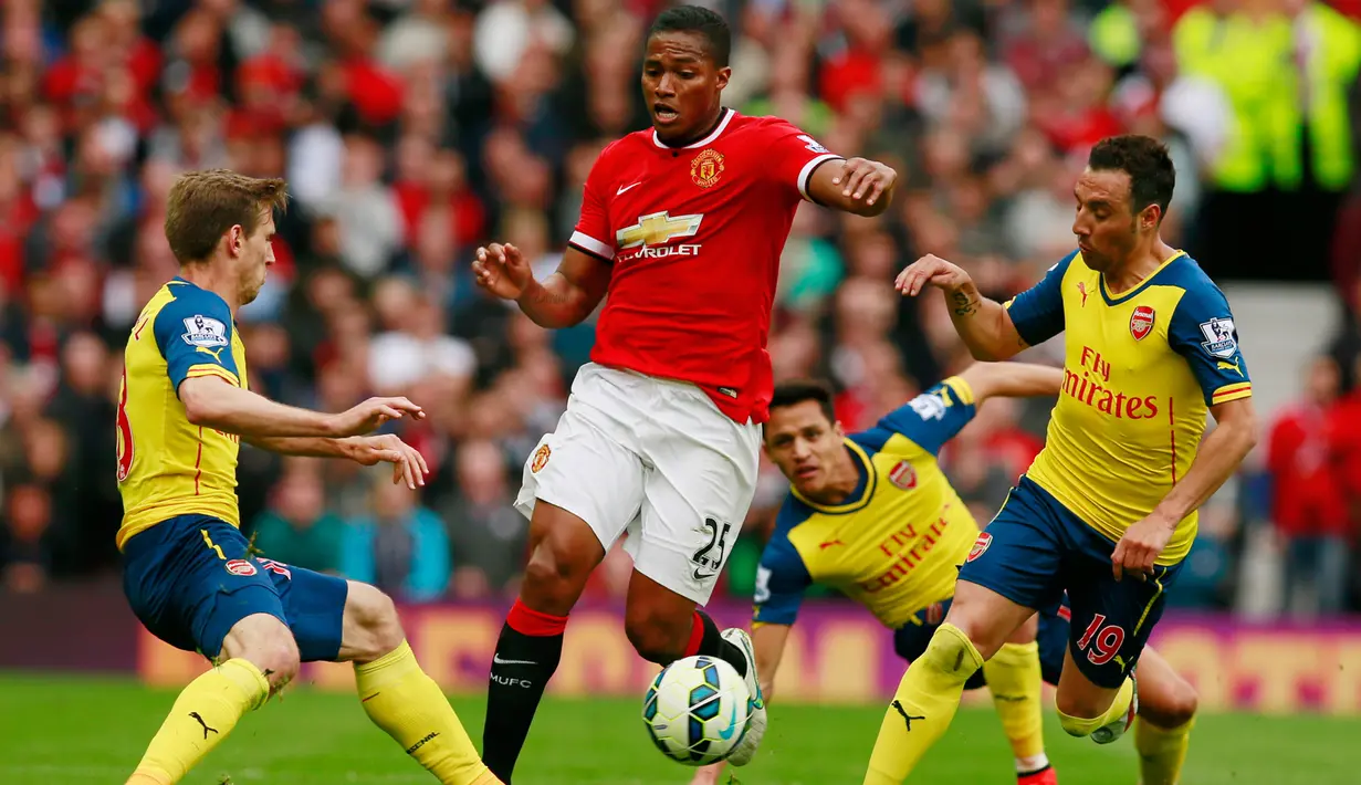 Gelandang Manchester United, Antonio Valencia (tengah) berusaha melewati dua pemain Arsenal saat Laga Liga Premier Inggris di Stadion Old Trafford, Minggu (17/5/2015). Manchester United bermain imbang 1-1 atas Arsenal. (Reuters/Jason Cairnduff)