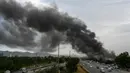 Pengendara melintas di sebuah jalan ketika asap membumbung dari kebakaran yang terjadi di sebuah pasar mingguan di Islamabad pada tanggal 10 Juli 2024. (Aamir Qureshi/AFP)