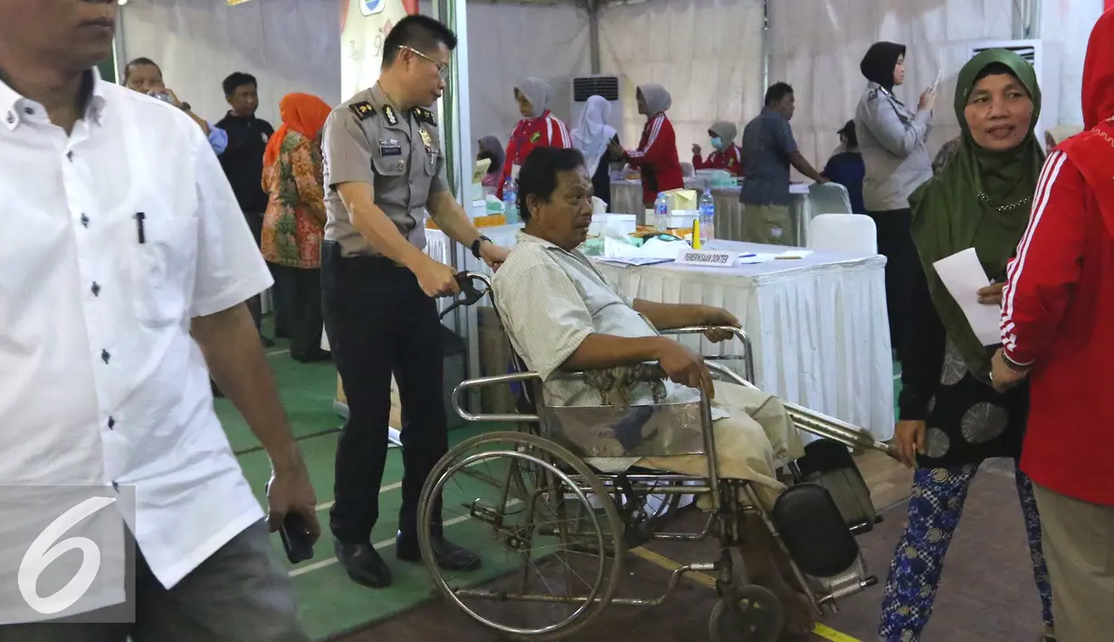 Warga dibantu petugas saat mengikuti pengobatan gratis di Gor Cendrawasih, Jakarta, (23/7). Acara ini memperingati HUT ke-70 Bhayangkara dengan menggelar pengobtan gratis, sunatan masal, donor darah dan periksa gigi gratis. (Liputan6.com/Angga Yuniar)