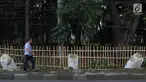 Warga melintas di samping pagar yang ambruk di Taman Hutan Tebet, Jakarta, Kamis (28/3). Kondisi pagar yang ambruk akibat hujan deras tersebut butuh perbaikan karena telah terabaikan selama beberapa bulan terakhir. (Liputan6.com/Immanuel Antonius)