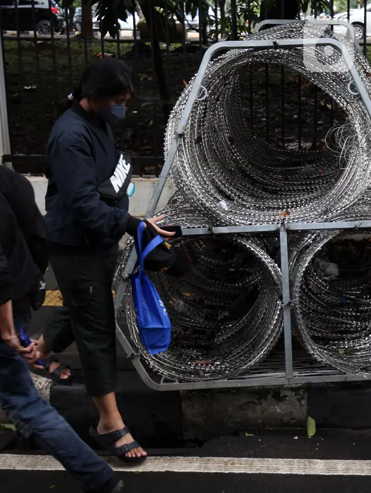 Pejalan kaki berjalan menghindari kawat berduri yang berada di trotoar Jalan Asia Afrika, Jakarta Pusat, Selasa (28/12/2021). Kawat berduri yang berada di trotoar tersebut sangat mengganggu para pejalan kaki yang melintas. (Liputan6.com/Johan Tallo)