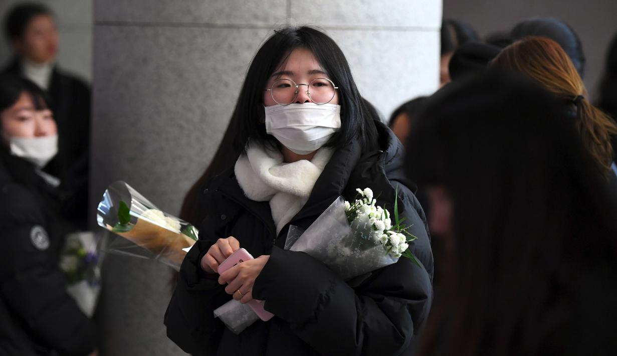 Seorang fans datang membawa bunga untuk memberikan penghormatan kepada Jonghyun SHINee di rumah duka Seoul Asan Hospital, Selasa (19/12). Kepergian Jonghyun SHINee ini menjadi pukulan mendalam bagi keluarga, sahabat, dan penggemar. (JUNG Yeon-Je / AFP)