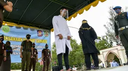 Salah seorang pasangan terpidana kasus zina (tengah) menjalani hukuman cambuk di Masjid Al Munawarah, Kota Jantho, Aceh Besar, Jumat (4/9/2020). Pasangan terpidana yang terbukti melanggar Syariat Islam dalam kasus zina itu masing masing menjalani sebanyak 100 cambuk. (CHAIDEER MAHYUDDIN/AFP)