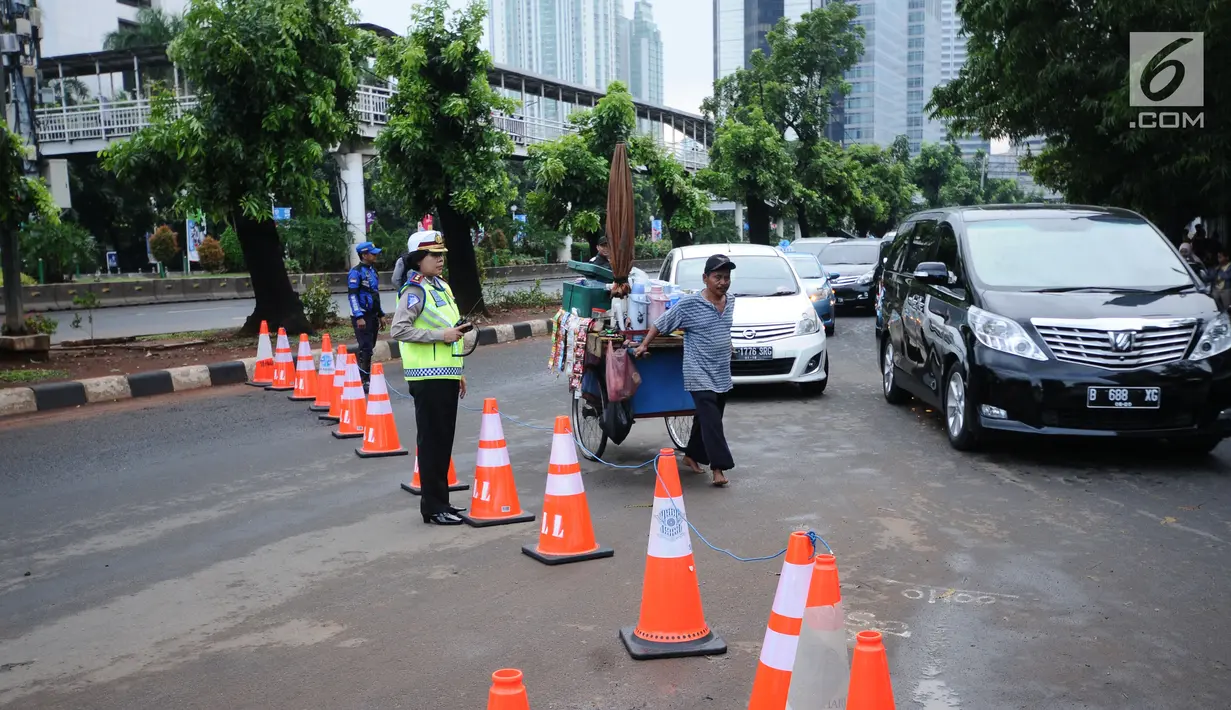 Petugas kepolisian berjaga saat pengalihan arus di Jalan Jenderal Sudirman, Jakarta, Minggu (31/12). Pengalihan terkait malam puncak perayaan pergantian tahun di kawasan Bundaran HI hingga Jalan MH Thamrin. (Liputan6.com/Helmi Fithriansyah)