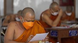 Seorang Biksu Buddha memakai masker untuk membantu melindungi diri dari virus corona, mengikuti tes bahasa Pali liturgi di Wat Molilokayaram di Bangkok, Thailand, Kamis (20/1/2022). (AP Photo/Sakchai Lalit)