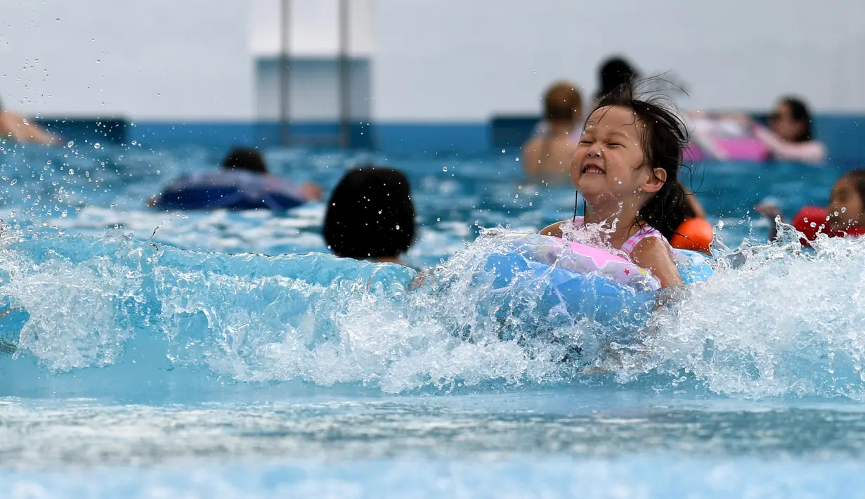 Seorang anak bermain di kolam renang di sebuah taman hiburan di Tokyo, Jepang (19/7). Badan Meteorologi Jepang mengumumkan Jepang tengah, termasuk Tokyo, telah menyelesaikan musim hujan 'Tsuyu'.  (AFP Photo/Toshifumi Kitamura)