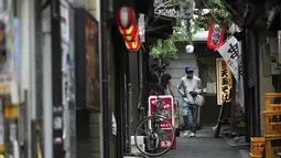 Seorang pria yang mengenakan masker untuk membantu mengekang penyebaran virus corona berjalan di sepanjang jalan bar yang kosong di Tokyo, Selasa (22/6/2021). Ibu kota Jepang mengkonfirmasi lebih dari 430 kasus virus corona baru pada hari Selasa. (AP Photo/Eugene Hoshiko)