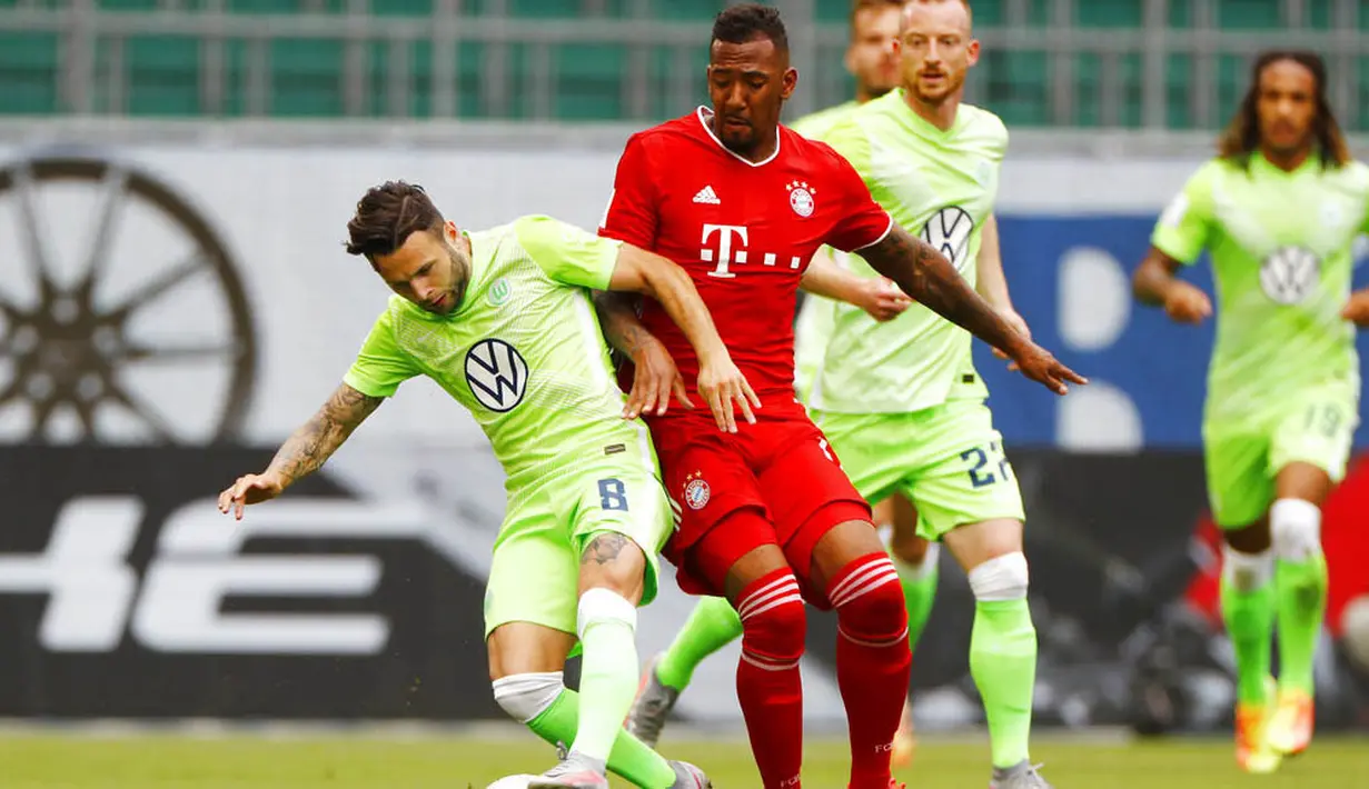 Pemain Bayern Munchen, Jerome Boateng, berebut bola dengan pemain Wolfsburg, Renato Steffen, pada laga Bundesliga di Volkswagen Arena, Sabtu (27/6/2020). Bayern menang dengan skor 4-0. (AP/Kai Pfaffenbach)